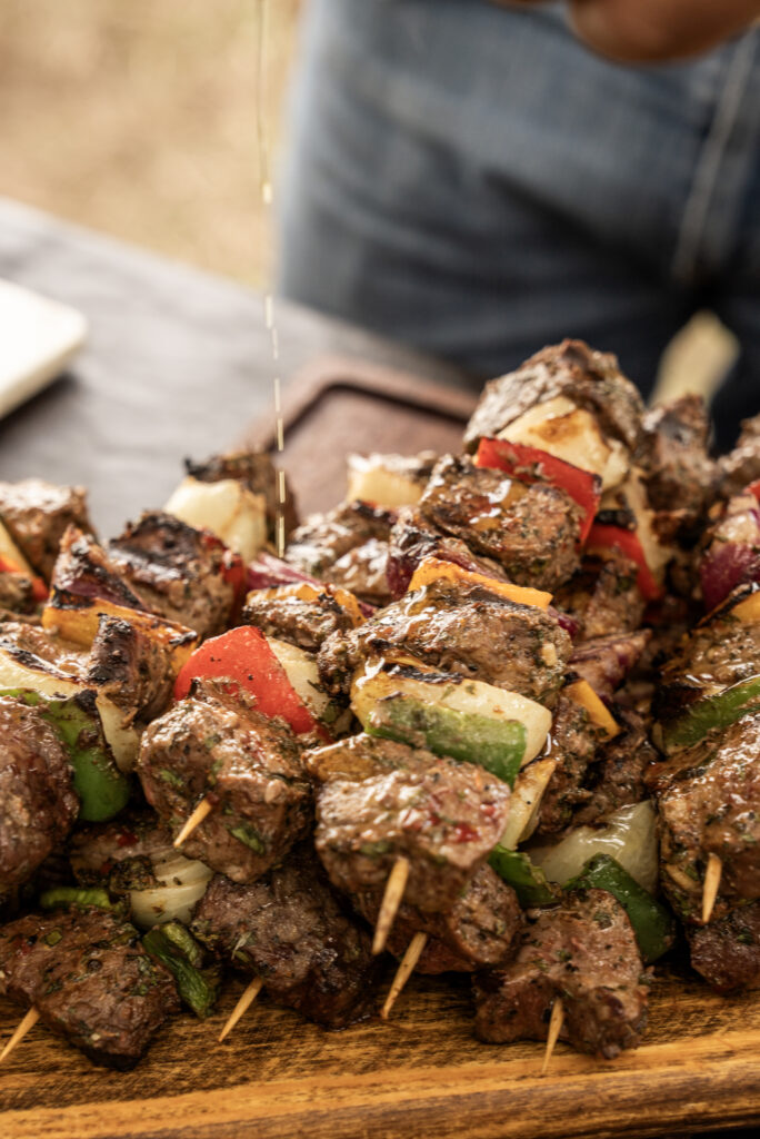 Close-up of freshly prepared meat and vegetable brochettes arranged on a wooden serving board.