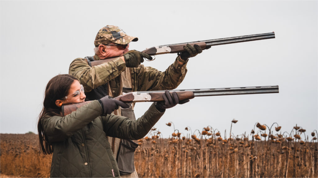 Two hunters aiming shotguns during a dove hunting trip in Argentina.